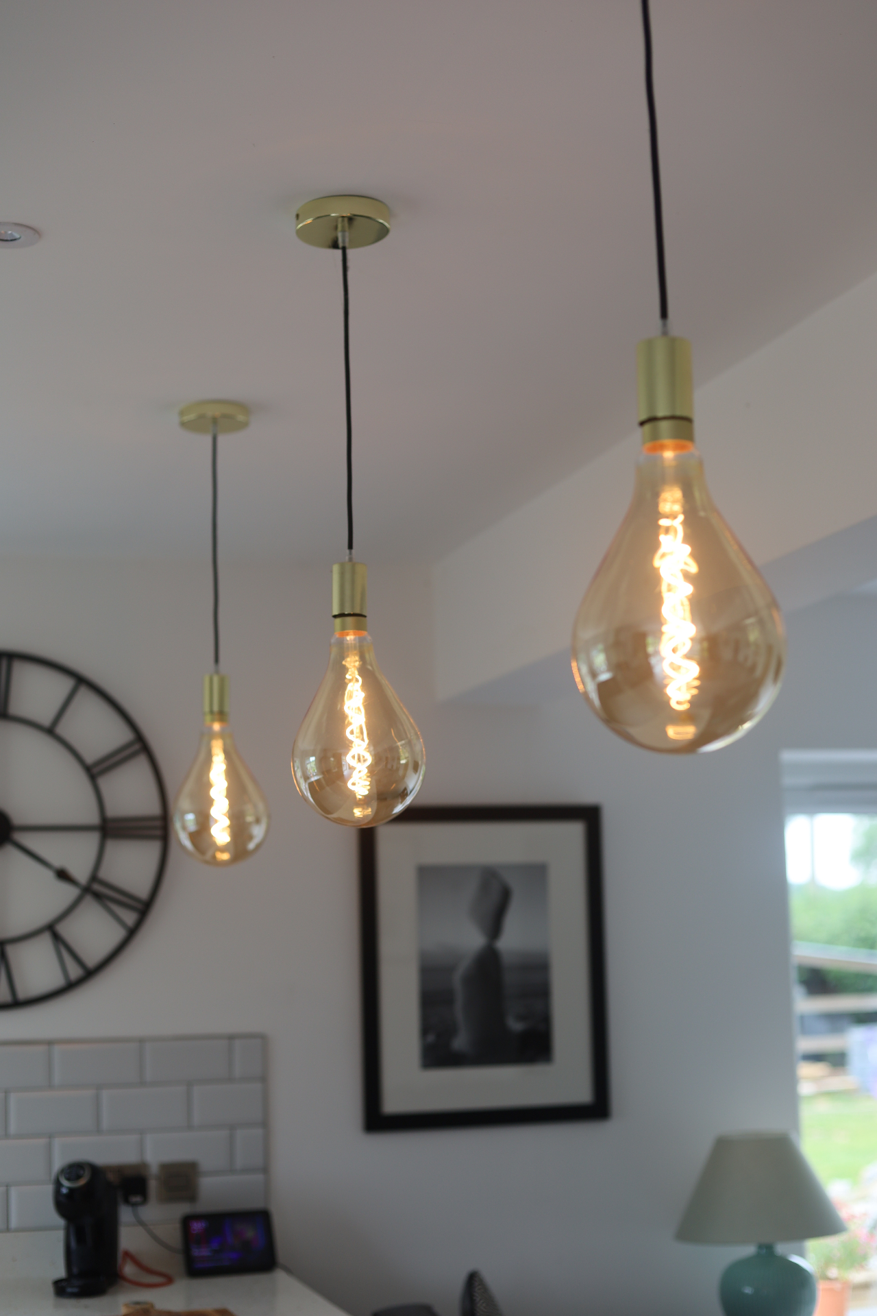 Trio of pendant gold filament bulbs against a bright interior